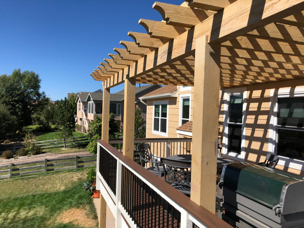 Wooden pergola on sunny backyard deck.