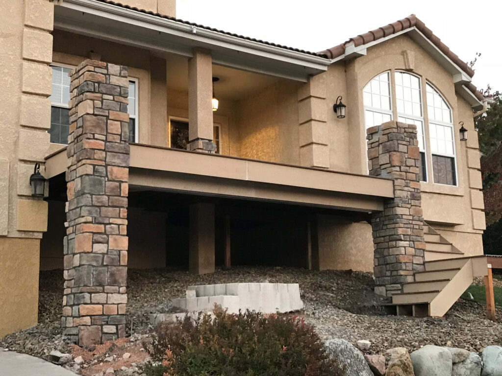 Stone-columned porch with stairs and windows.